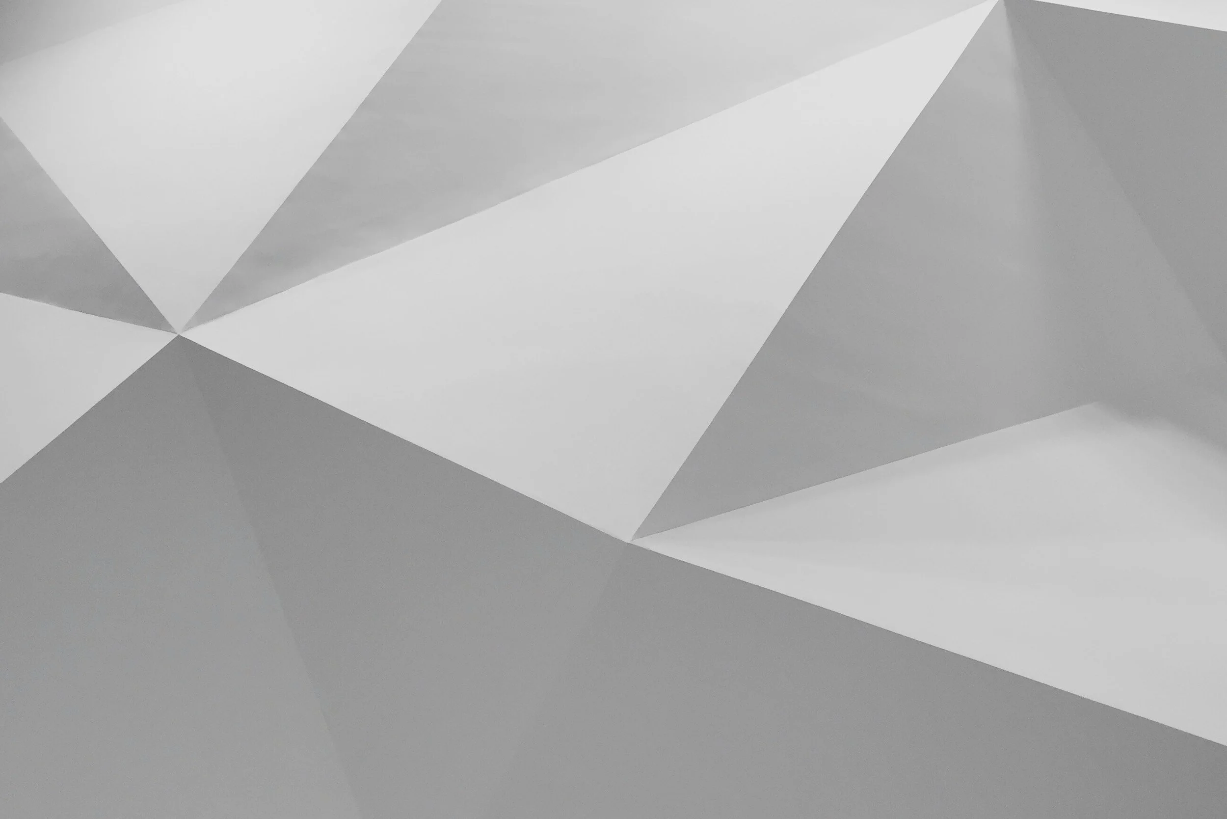 A grayscale abstract geometric pattern with various triangles and polygons.