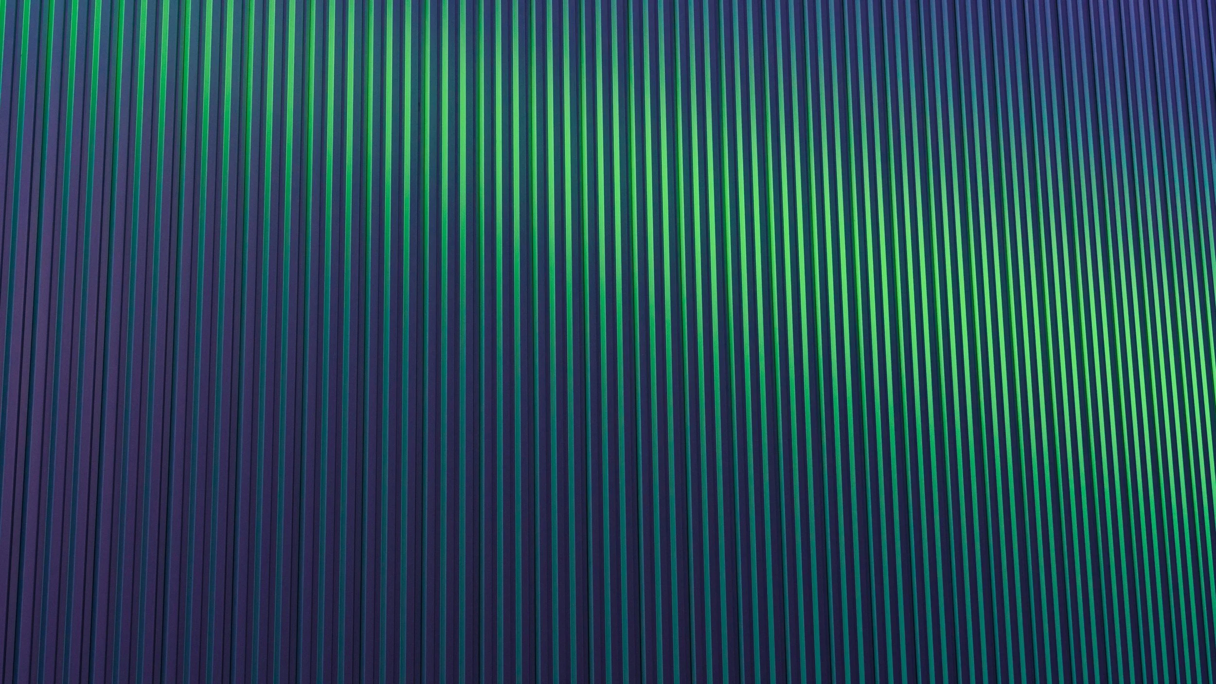 Close-up of a surface with evenly spaced vertical ridges in shades of blue, green, and purple.